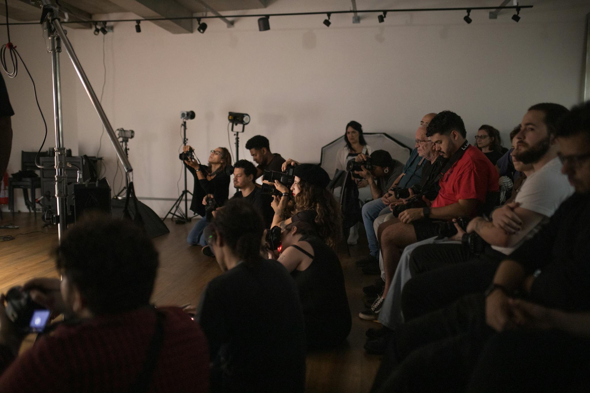 A group of photographers attentively engaged in a photography workshop indoors.